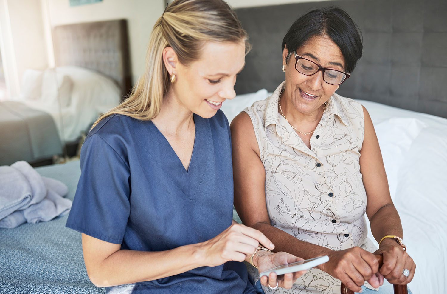 Young care worker with elderly women on phone