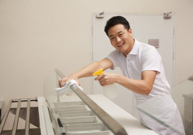 Cafeteria worker cleaning food serving area