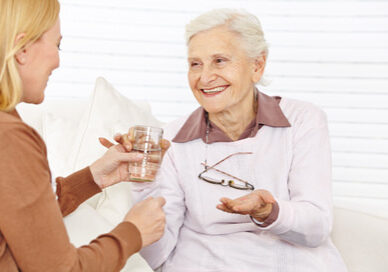 Smiling senior citizen woman taking medical pill with a cup of water