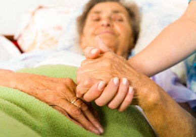 Health care nurse holding elderly lady's hand with caring attitude.